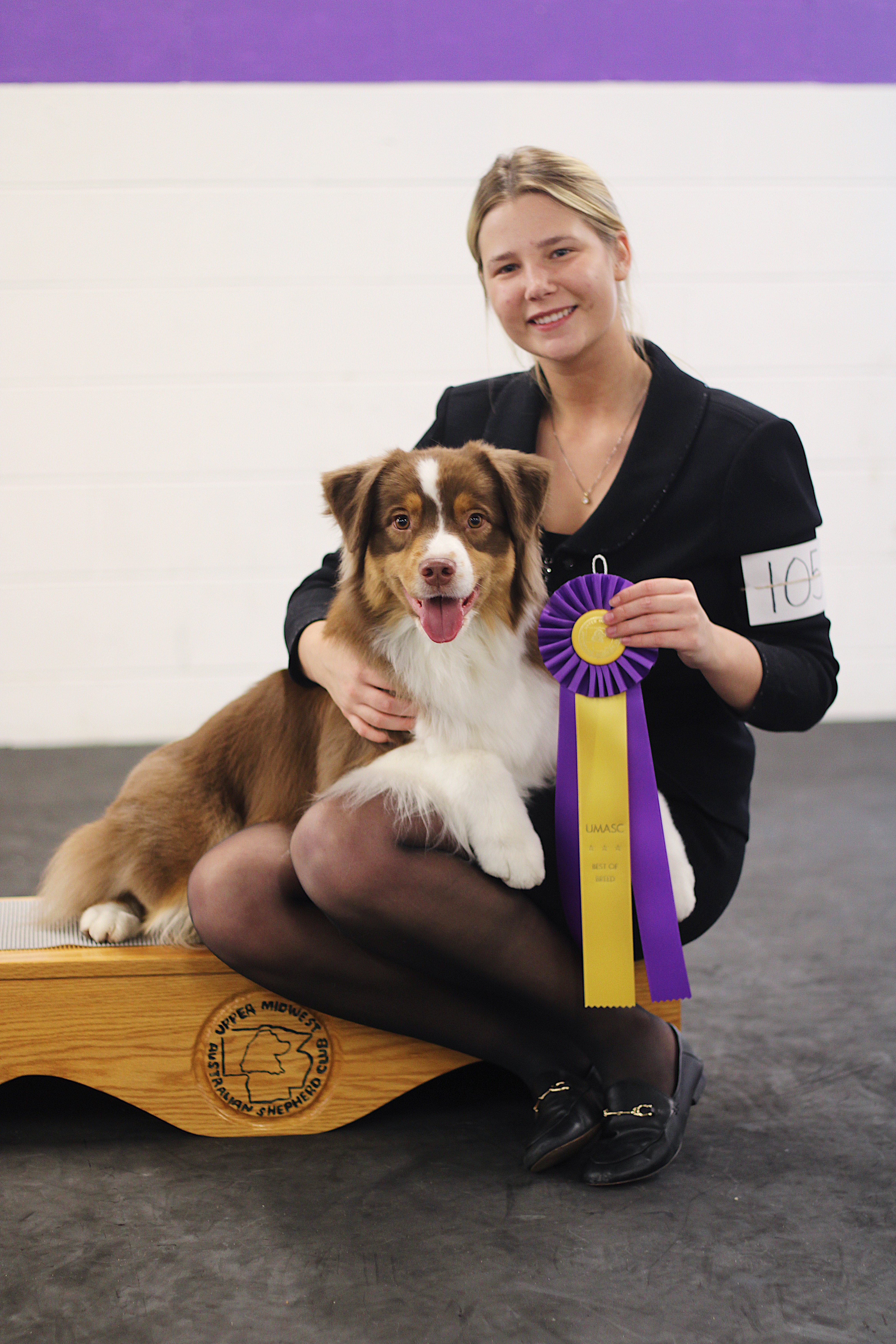 Handler with red tri Aussie and UMASC Best of Breed rosette